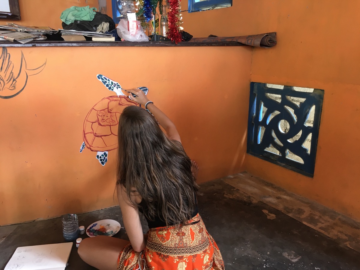 Lena painting a turtle on the wall of place where they stayed
